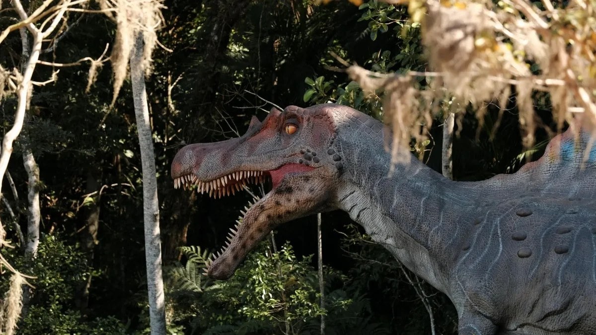 Dinosaurio animatrónico en el sendero que atraviesa el bosque del parque Aventura Jurásica