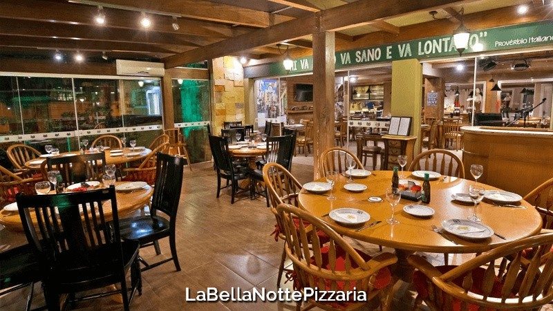 Salão em madeira da La Bella Notte Pizzaria com mesas postas para o rodízio, em Gramado