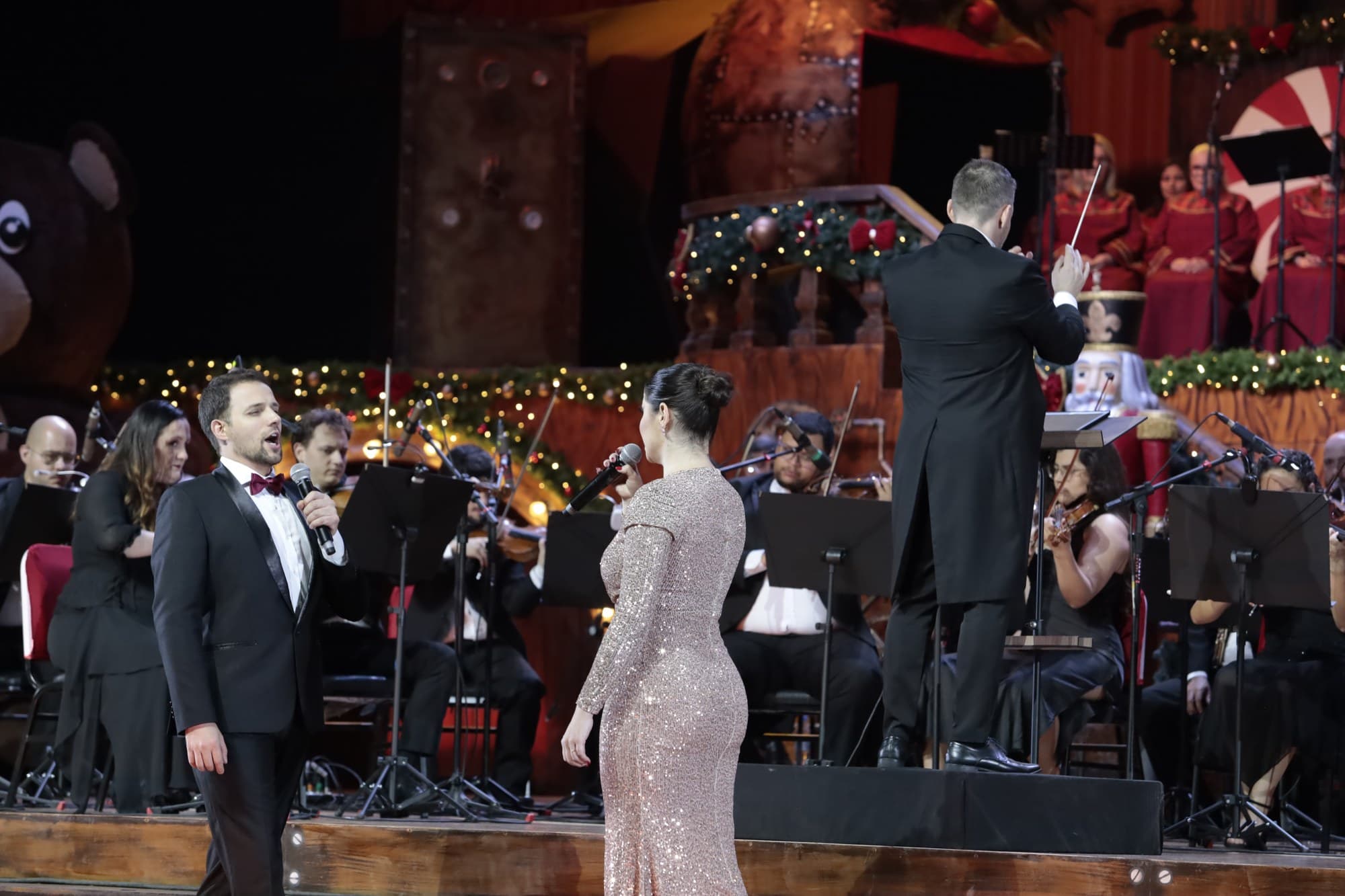 Cantora solista e naipe de cordas diante da árvore de Natal no Natal Luz In Concert, Gramado
