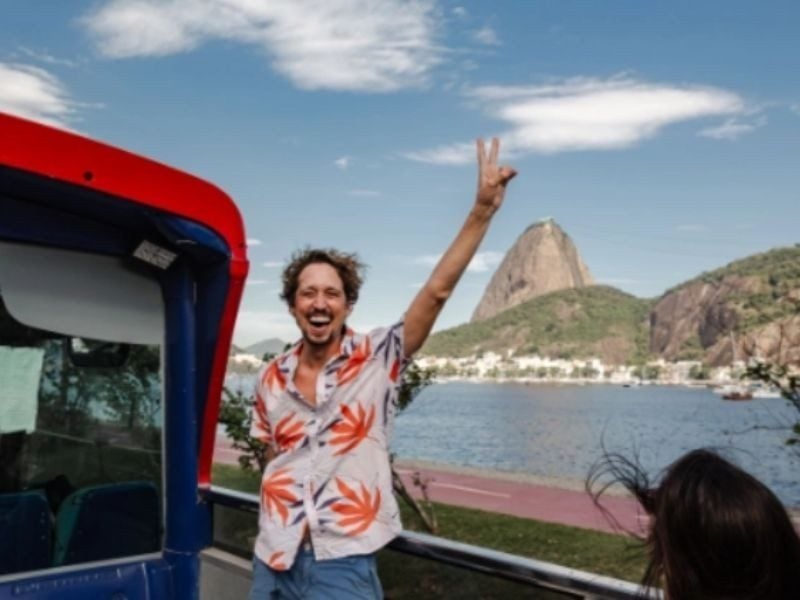 Turista no Rio Samba Bus com o Pão de Açúcar ao fundo, na Urca, Rio de Janeiro