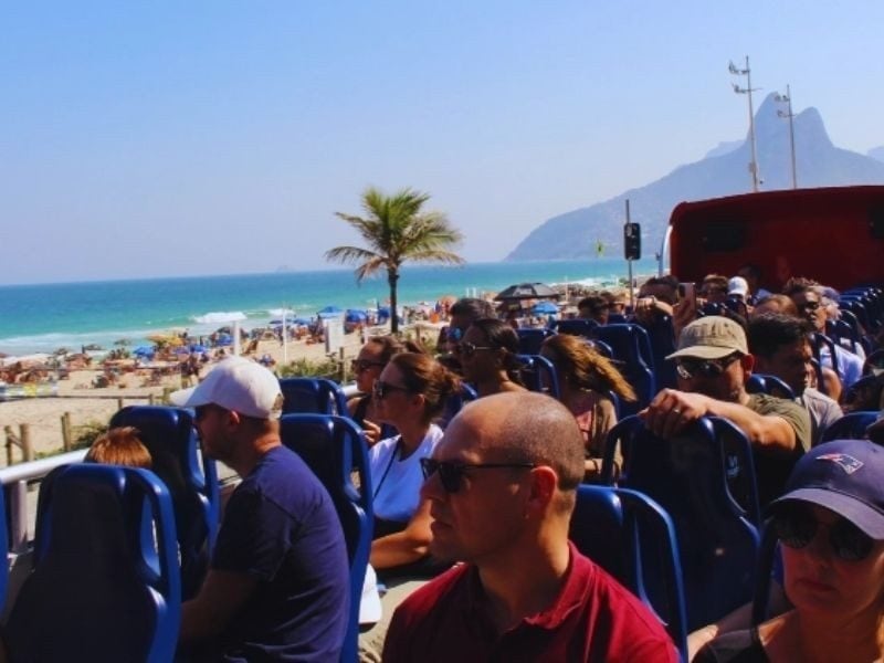 Passageiros do Rio Samba Bus na orla de Ipanema com o Morro Dois Irmãos ao fundo, Rio de Janeiro