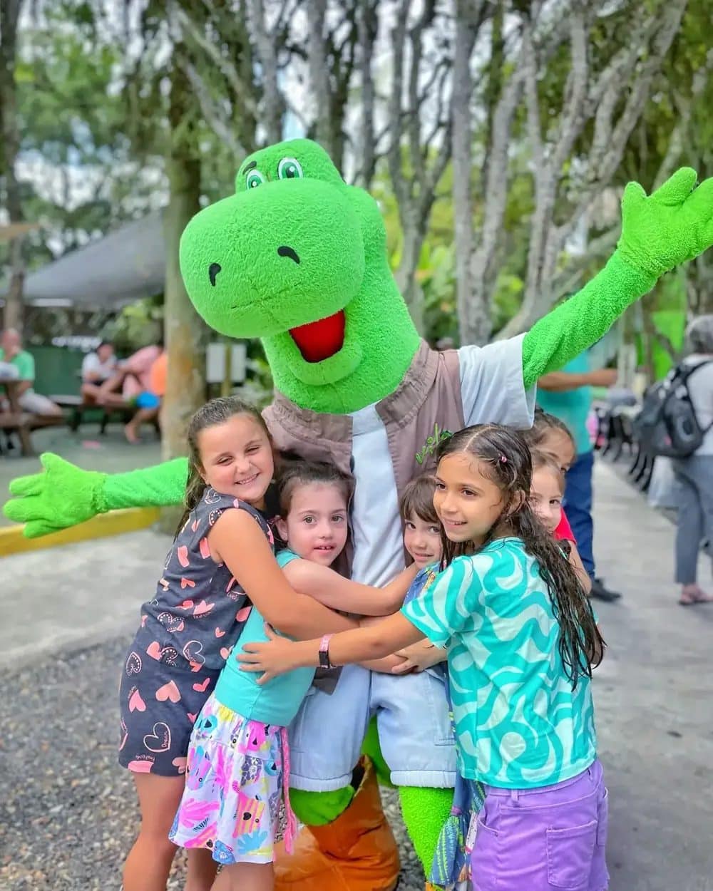 Crianças abraçando o Darwin, dinossauro mascote da Vila Encantada em Pomerode-SC
