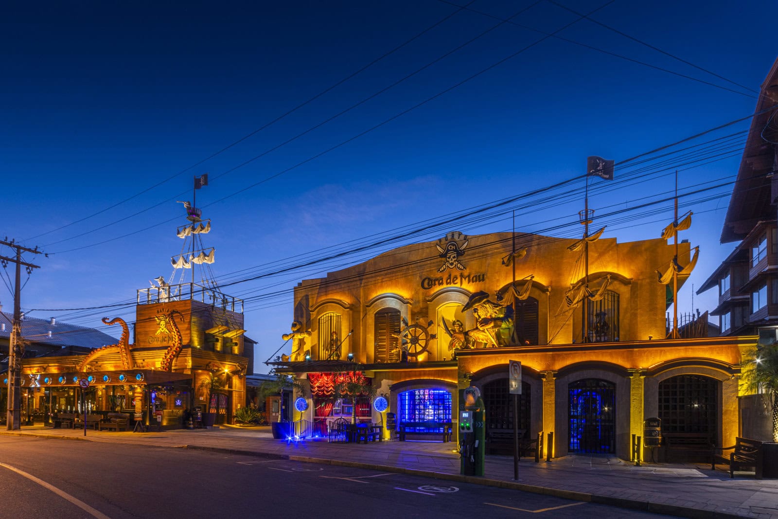 Fachada da Pizzaria Cara de Mau iluminada à noite, com os ambientes Porto e Navio lado a lado no centro de Gramado