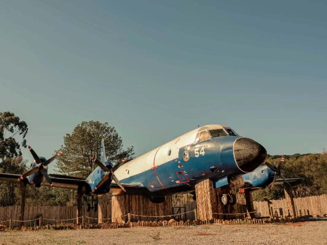 Avião de patrulha azul e branco entre as árvores no Jardim Secreto do Capitão – cupom OVIAJANTE com 5% de desconto