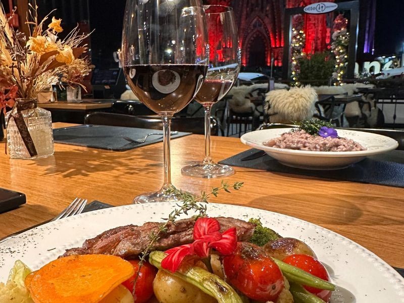 Filé com legumes e taça de vinho tinto no salão do Otto Bistrot em Canela
