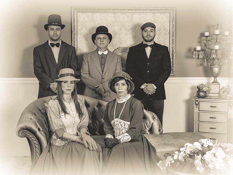 Família de cinco pessoas com trajes do século XIX em foto sépia na Recordar Fotos em Gramado