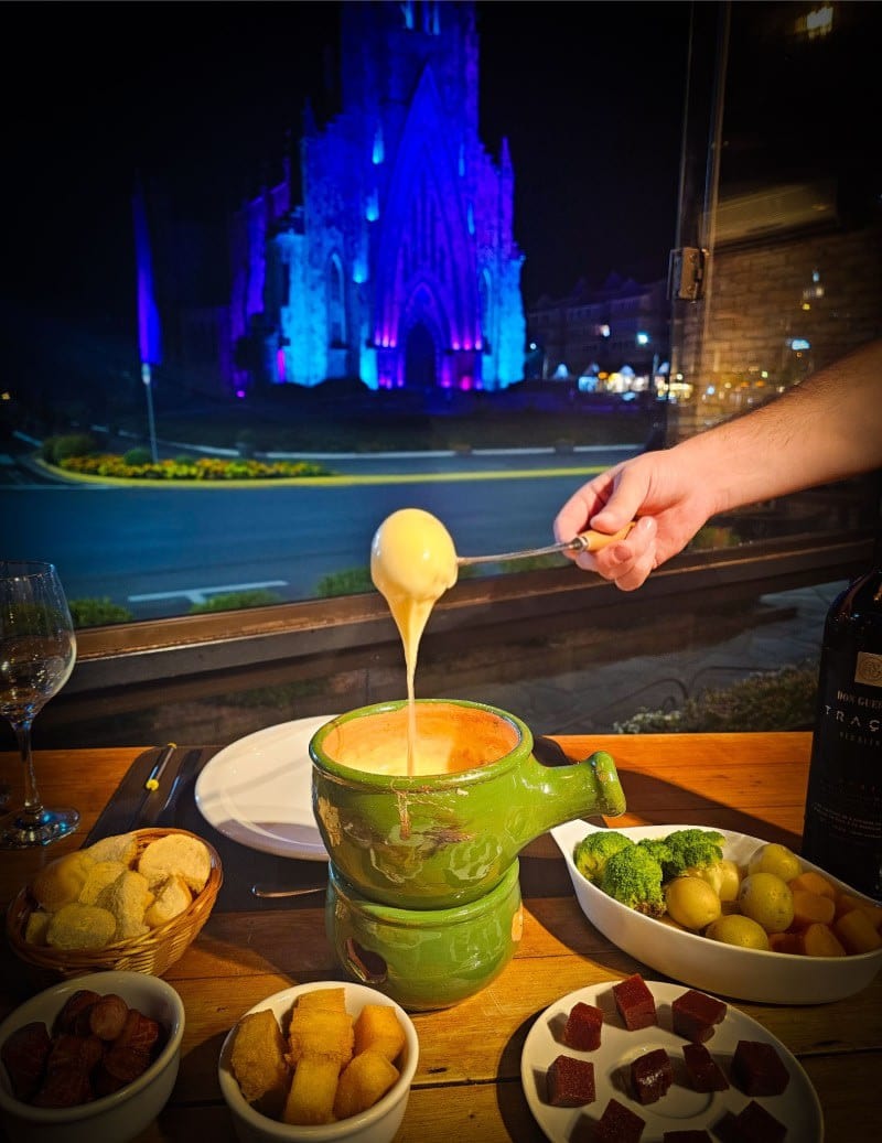 Fondue de queijo servido no Sello Restaurante com a Catedral de Pedra ao fundo