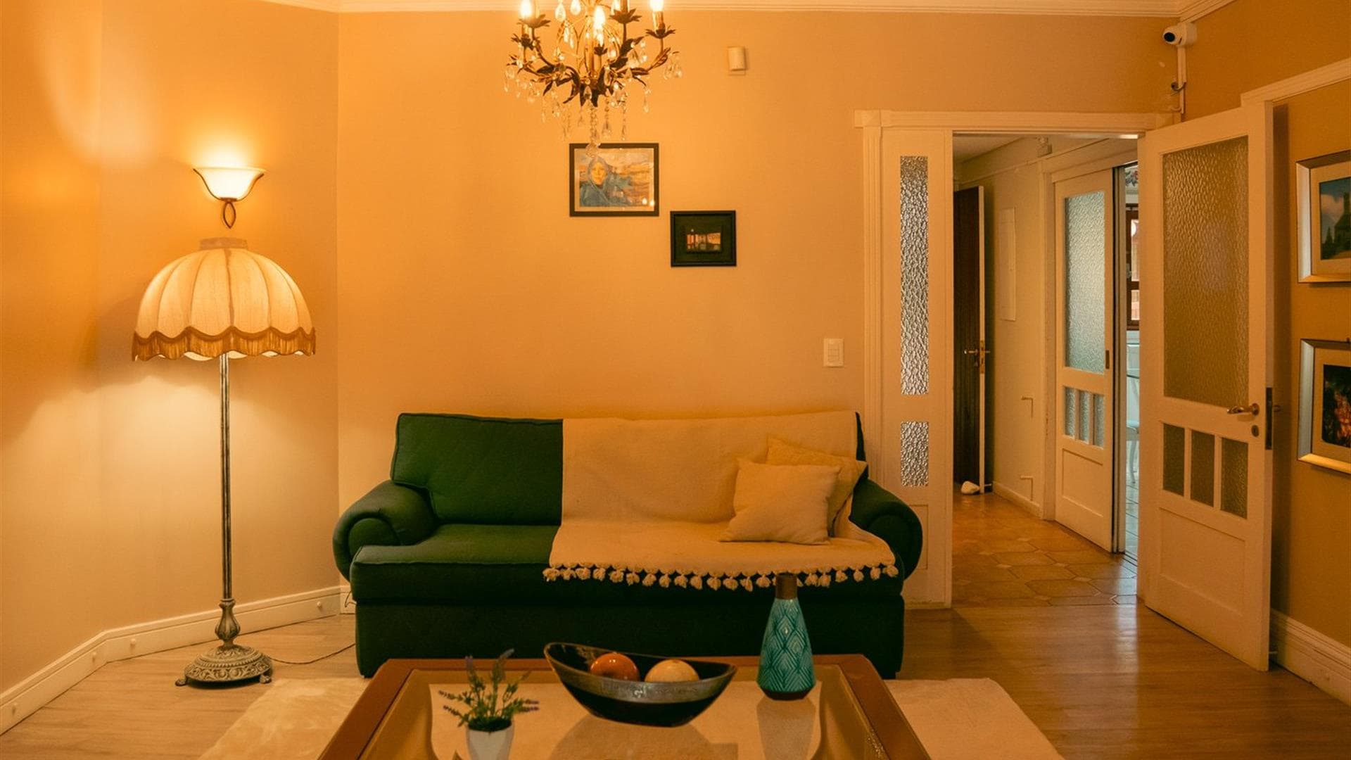 Sala de estar com sofá verde e lustre da Vivares Pousada Boutique Gramado, em Gramado