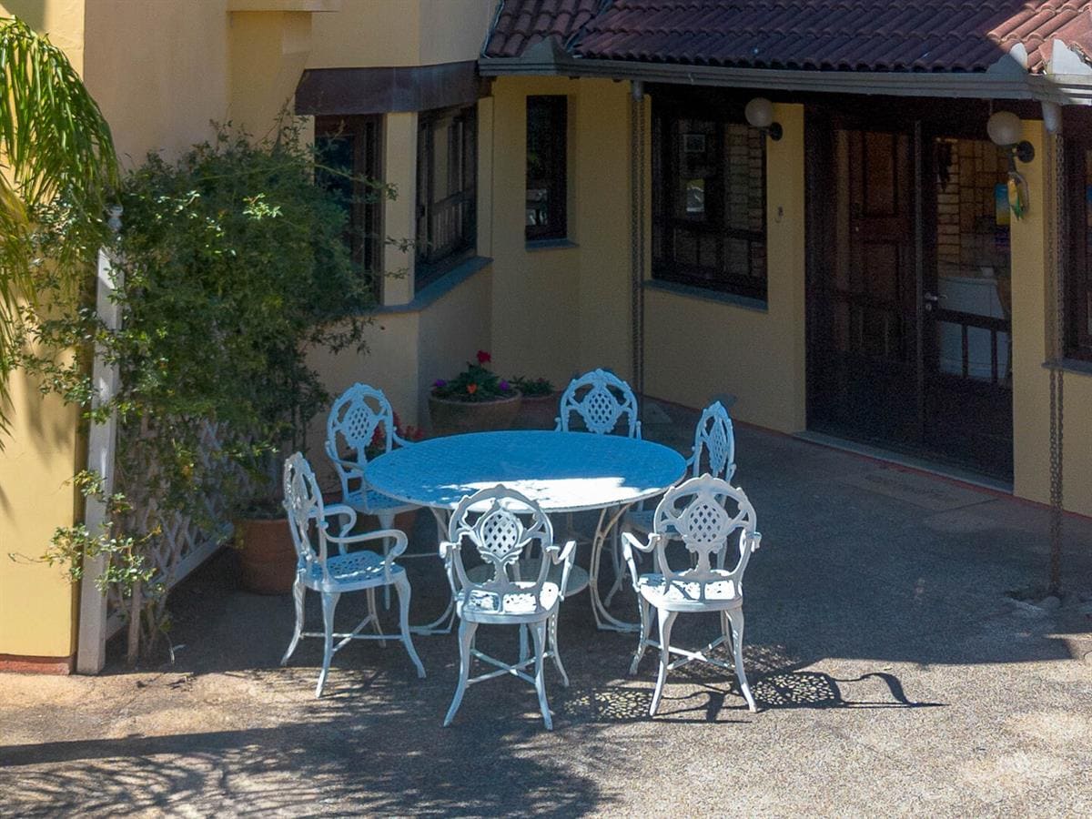 Pátio externo com mesa e cadeiras de ferro da Vivares Pousada Boutique Gramado, em Gramado