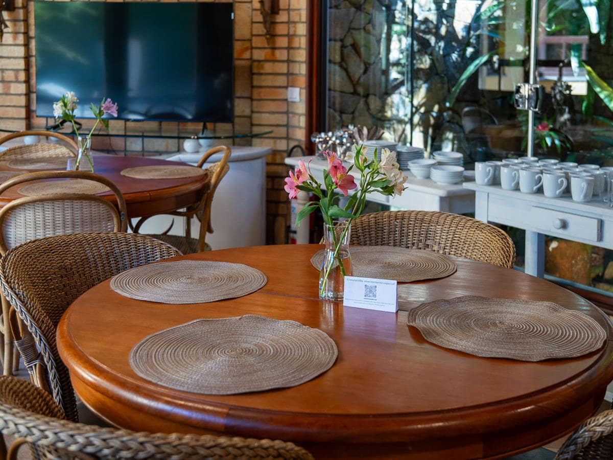 Sala do café da manhã com mesas de madeira da Vivares Pousada Boutique Gramado, em Gramado