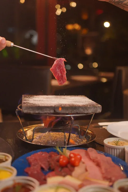 Carne sendo grelhada na pedra quente no fondue do Caquelon, em Canela