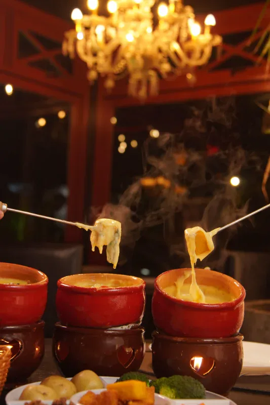 Fondue de queijo servido à luz do lustre no Caquelon Fondue Canela