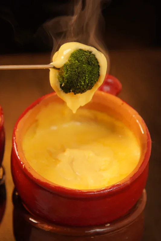 Brócolis coberto de queijo derretido no fondue do Caquelon, em Canela
