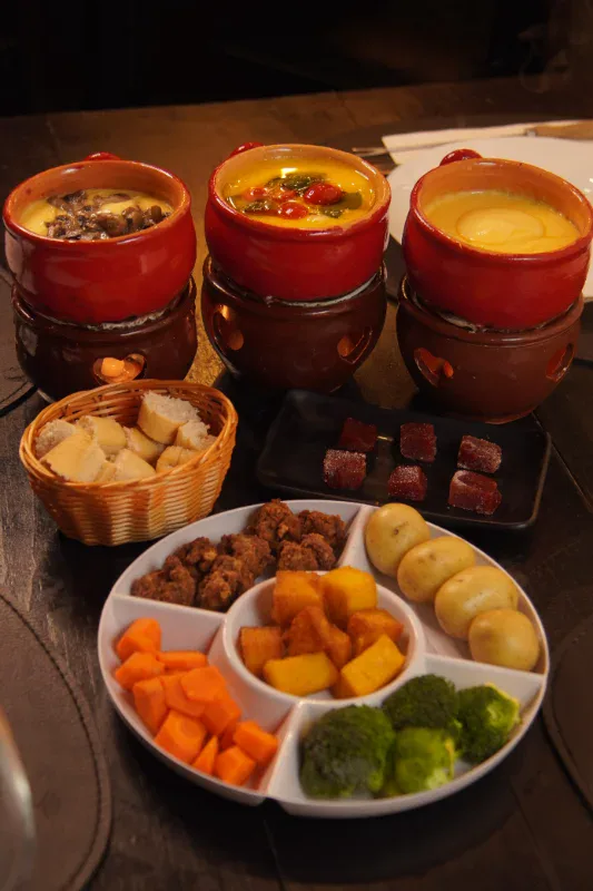 Três tipos de fondue de queijo com acompanhamentos da sequência Premium do Caquelon, em Canela