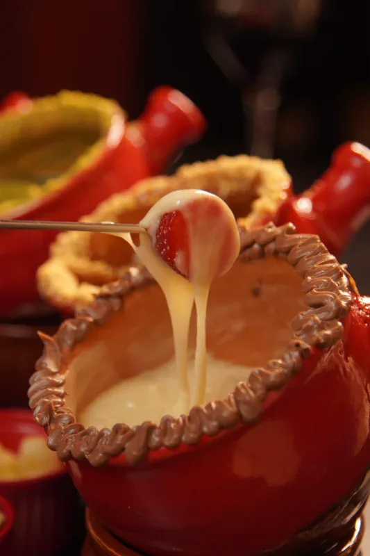 Morango mergulhado no fondue de chocolate branco do Caquelon Fondue, em Canela