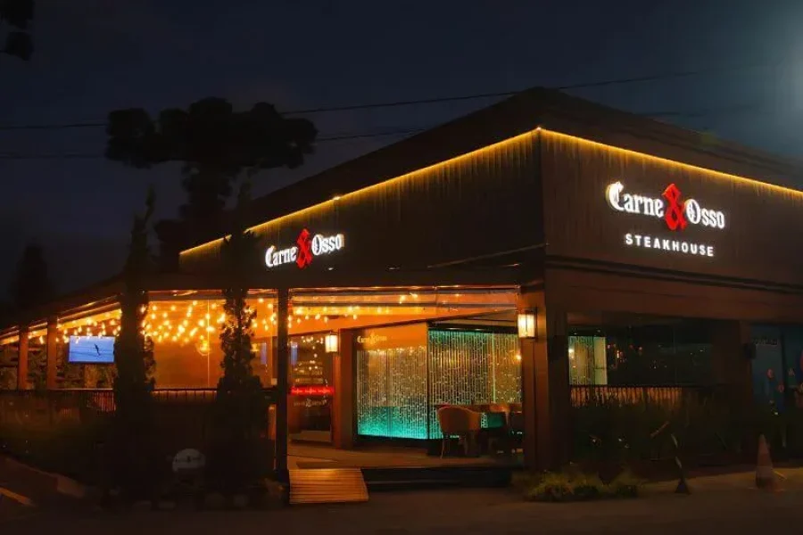 Fachada iluminada à noite do Carne & Osso Steakhouse, na Av. das Hortênsias, em Gramado
