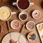 Fondue de chocolate branco e ao leite com frutas e confeitos na mesa do Chalezinho, em Gramado
