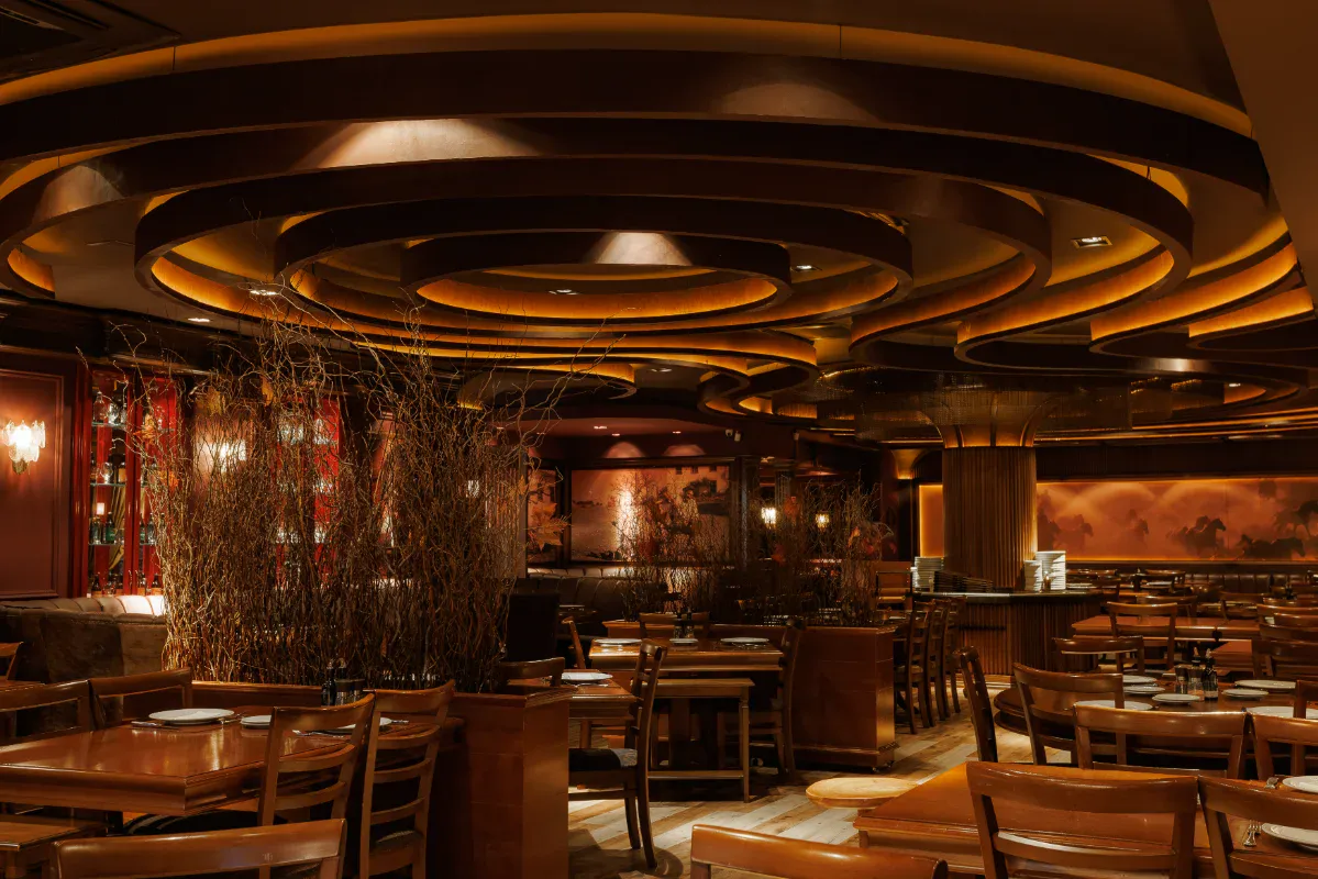 Salão principal da Churrascaria Chama de Fogo Gramado, com teto circular iluminado e mesas de madeira