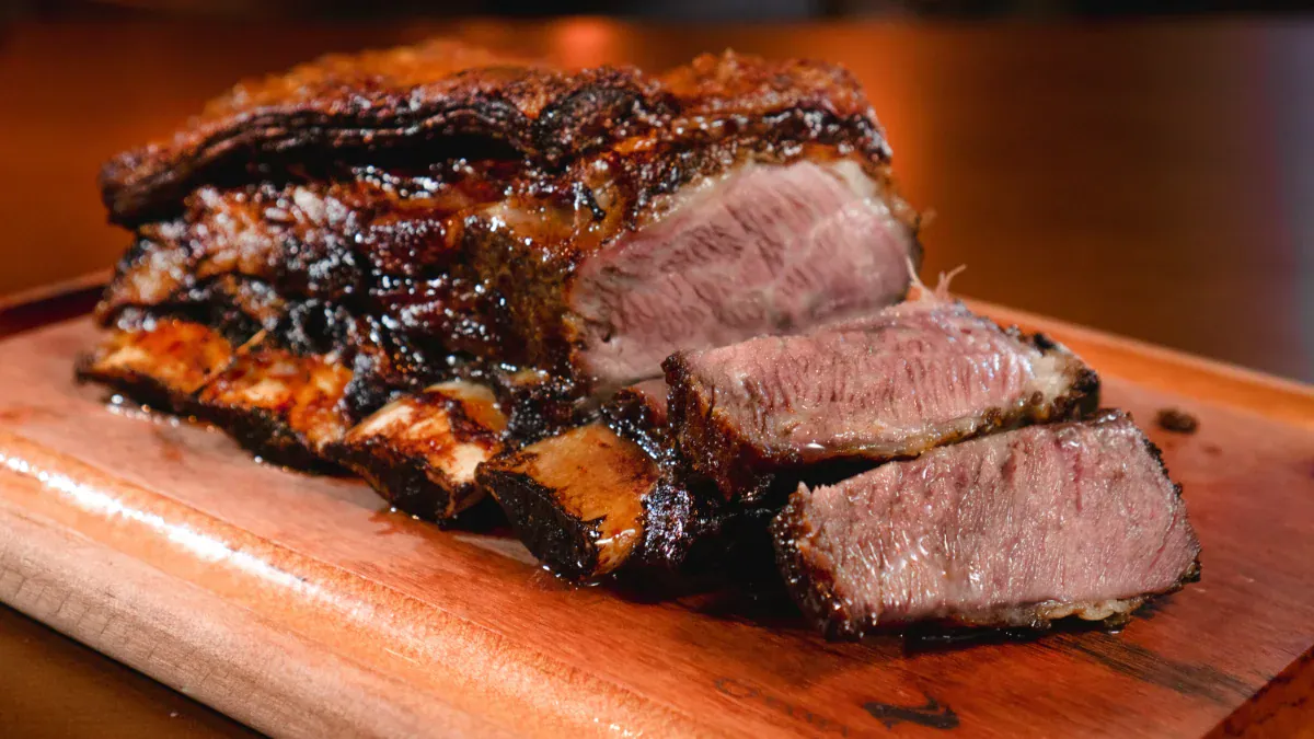 Costela assada fatiada sobre tábua de madeira no rodízio da Chama de Fogo Gramado
