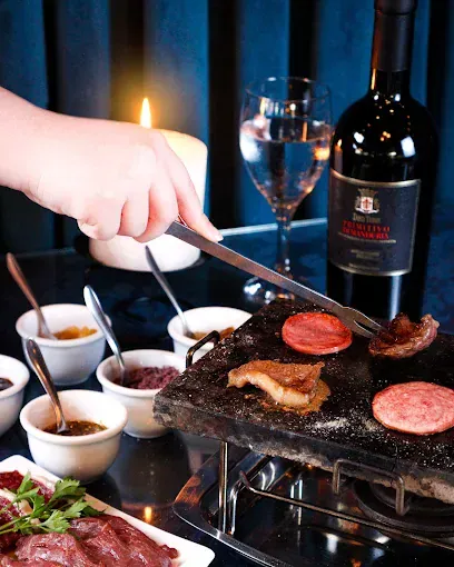 Carnes grelhando na pedra quente com molhos no fondue do Chaplins, em Gramado
