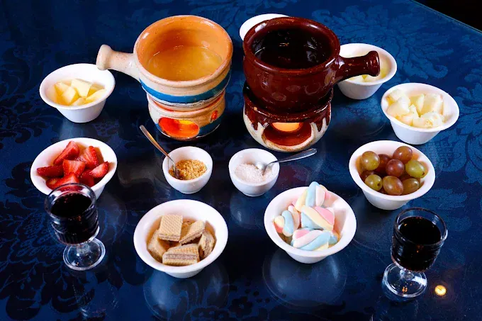 Fondue de chocolate preto e branco com frutas, wafer e marshmallow no Chaplins Fondue Gramado