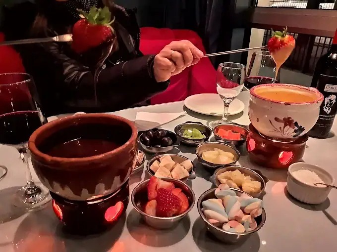 Casal mergulhando morango no fondue de chocolate do Chaplins Fondue, em Gramado