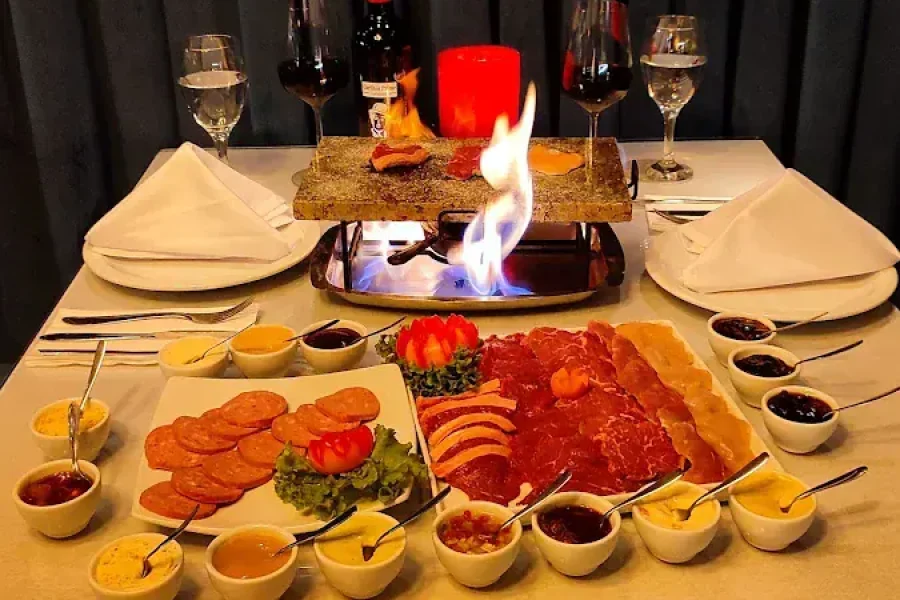 Mesa com a sequência completa de fondue de carnes e molhos do Chaplins, em Gramado