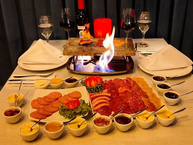 Mesa com a sequência completa de fondue de carnes e molhos do Chaplins, em Gramado