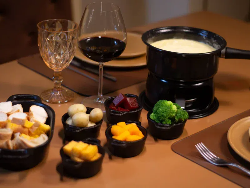 Mesa com fondue de queijo, queijos e acompanhamentos na sequência do Chocoland, em Gramado