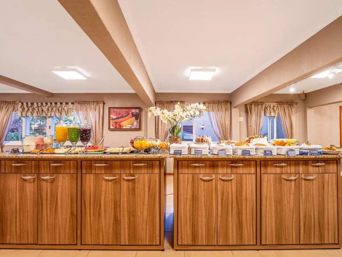 Buffet de café da manhã com sucos, frutas e bolos no Hotel Fioreze Quero Quero, em Gramado