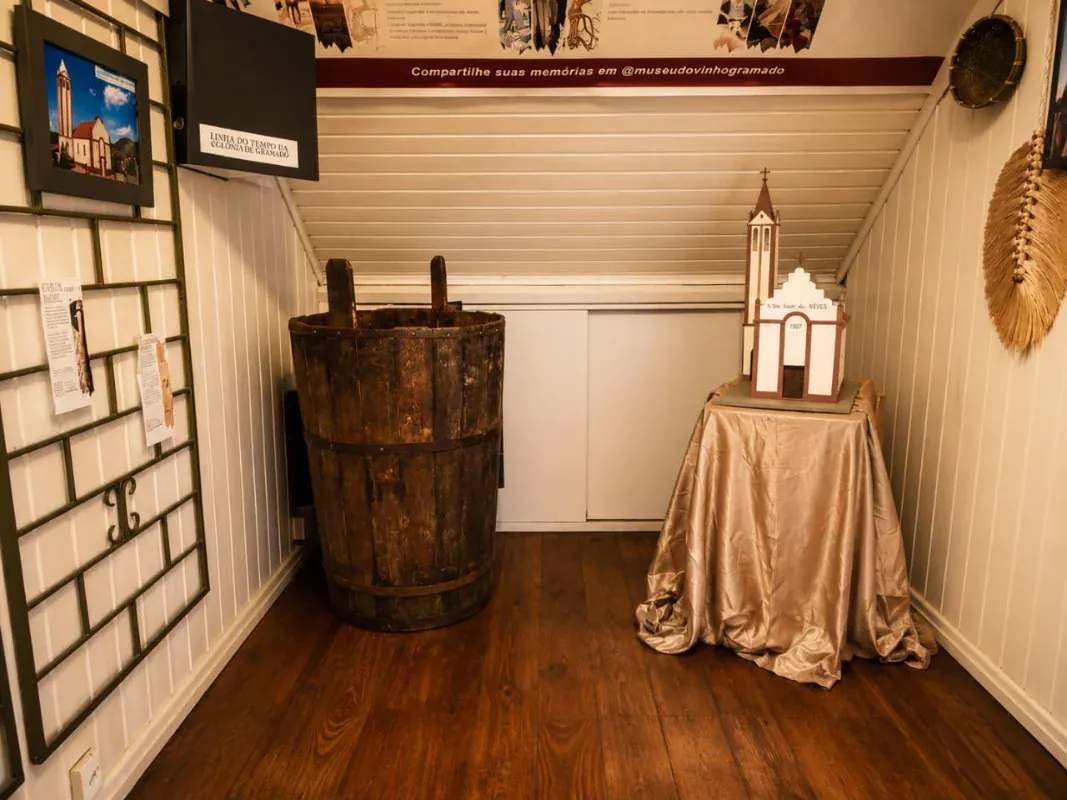 Mastela de madeira usada na pisa de uvas e maquete de igreja na exposição do Museu do Vinho Gramado