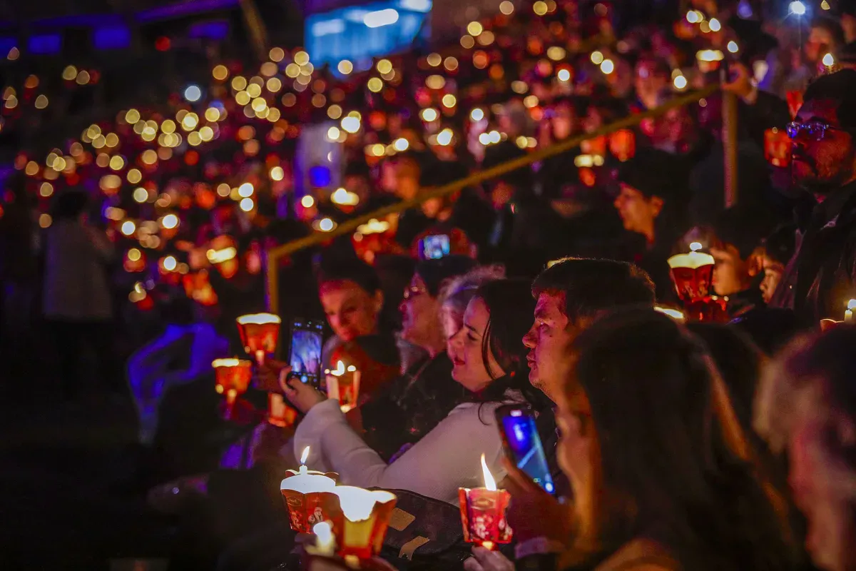 Público segurando velas acesas na plateia do Nativitaten, no Serra Park, em Gramado