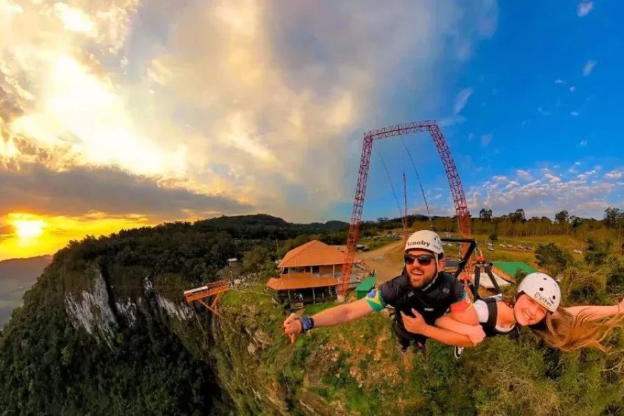 Casal no Superman do Parque Gasper, suspenso sobre o paredão ao pôr do sol em Bento Gonçalves