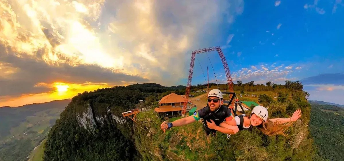 Casal no Superman do Parque Gasper, suspenso sobre o paredão ao pôr do sol em Bento Gonçalves