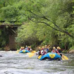 Botes de rafting descendo o Rio Paranhana sob uma ponte, no Brasil Raft Park, em Três Coroas
