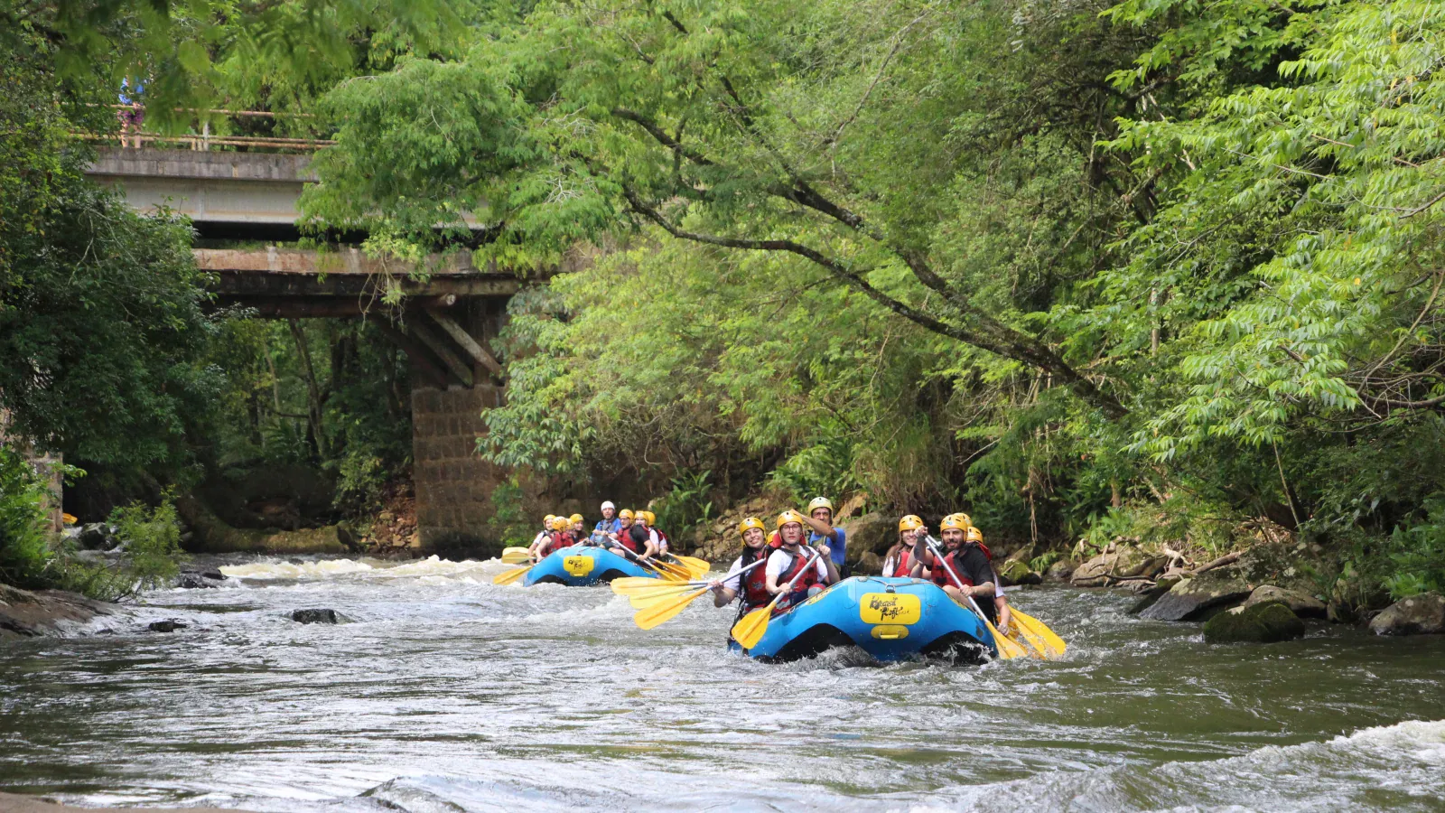 Botes de rafting descendo o Rio Paranhana sob uma ponte, no Brasil Raft Park, em Três Coroas