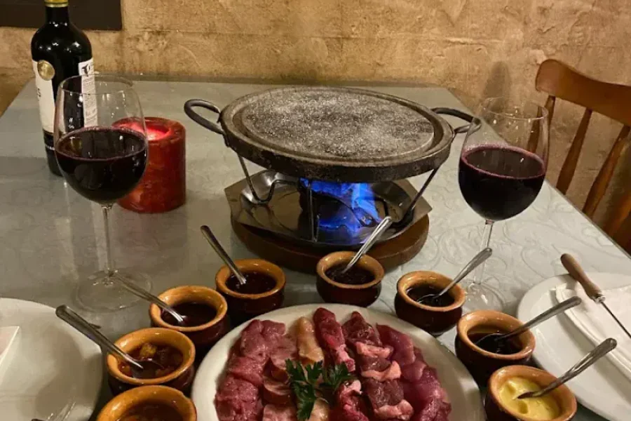 Fondue de carnes na pedra com molhos e vinho tinto no Reino da Boêmia, em Gramado