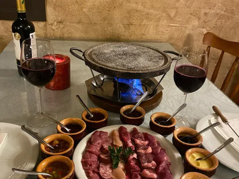 Fondue de carnes na pedra com molhos e vinho tinto no Reino da Boêmia, em Gramado