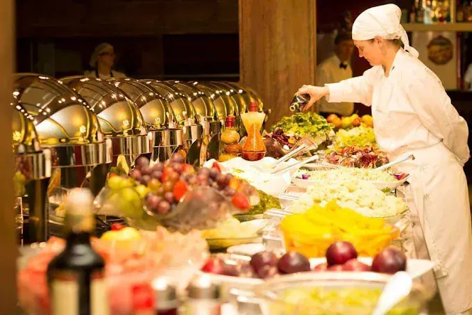 Chef serve o buffet com saladas, frutas e pratos quentes no Restaurante Lindenhof, em Nova Petrópolis